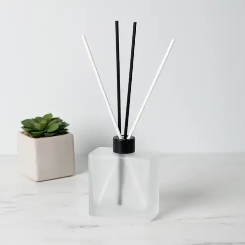 Frosted Square Reed Diffuser Bottle with Matte Black Reed Diffuser Collar and White and Black Fiber Diffuser Reeds on table